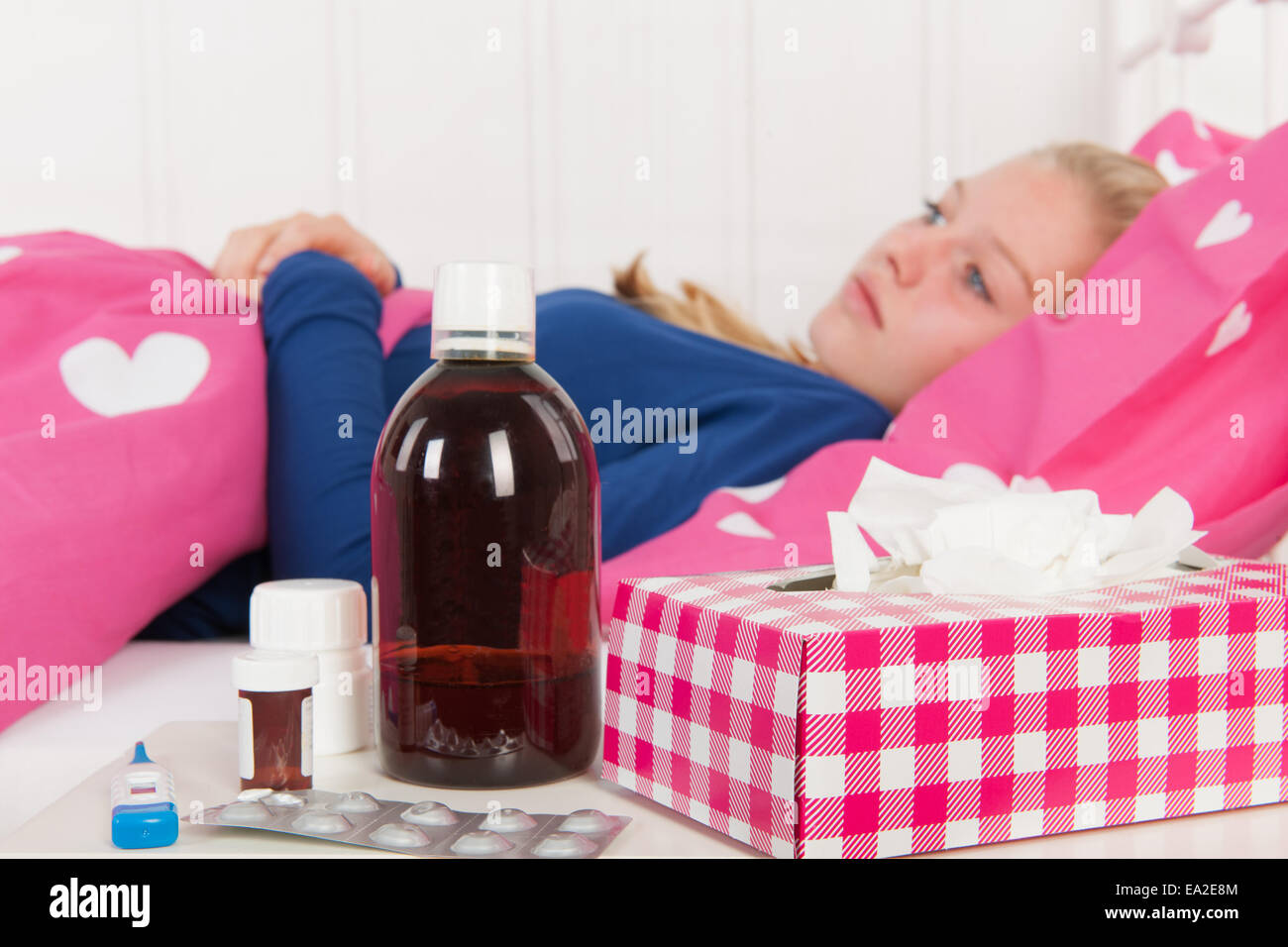Sick girl laying in bed with medicine à l'avant (l'accent sur la médecine) Banque D'Images