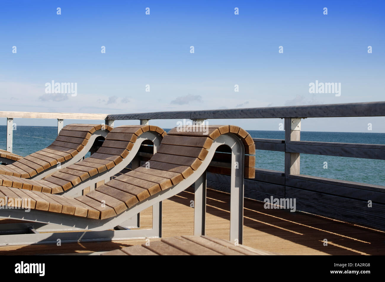 Des chaises longues en bois sur un pont sur la mer Banque D'Images