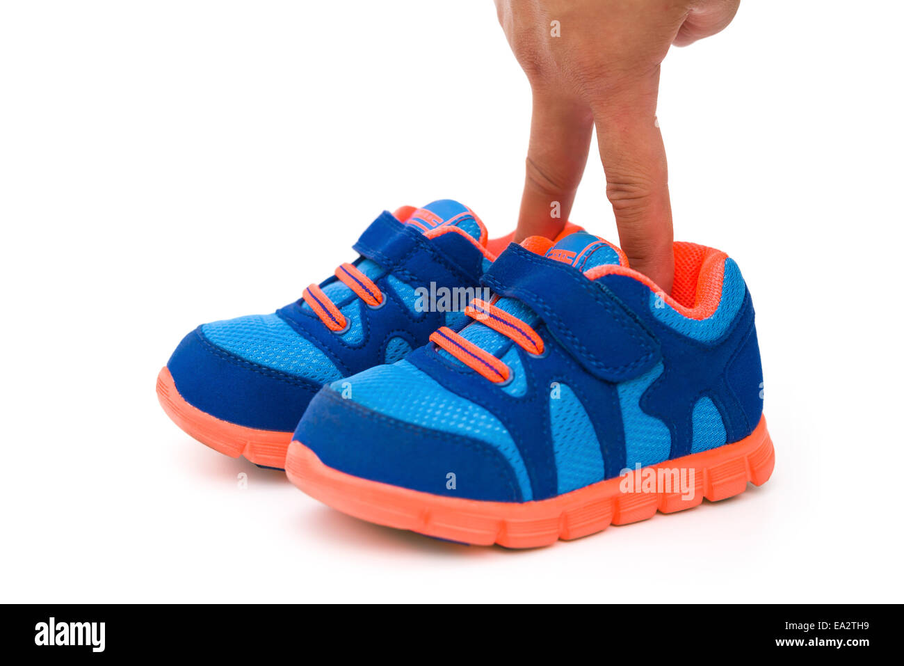 Mettre les doigts dans une paire de chaussures de sport pour enfant bleu sur blanc Banque D'Images