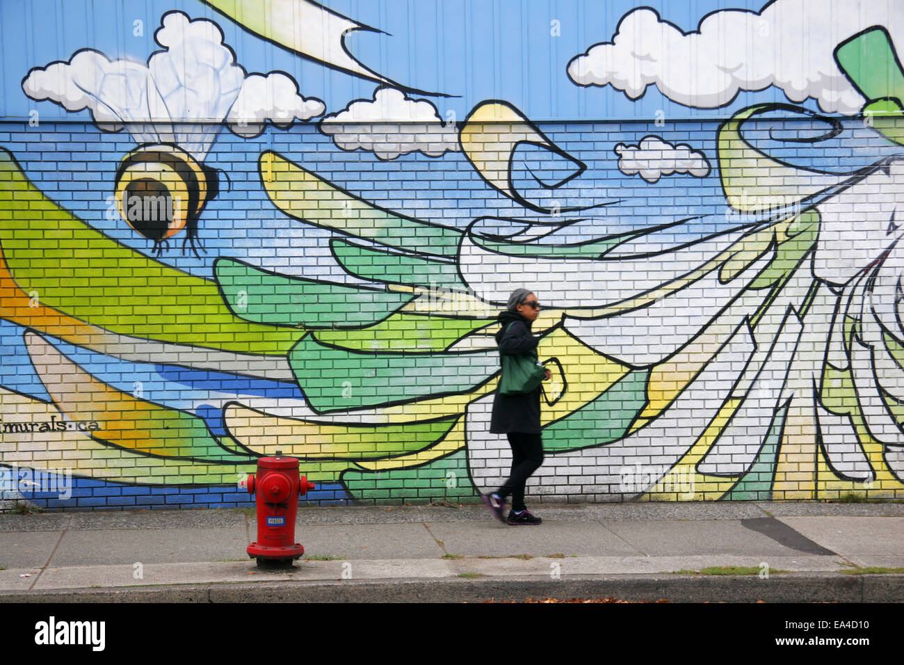 Femme marche passé une photo murale près de Main Street, Vancouver, Canada Banque D'Images