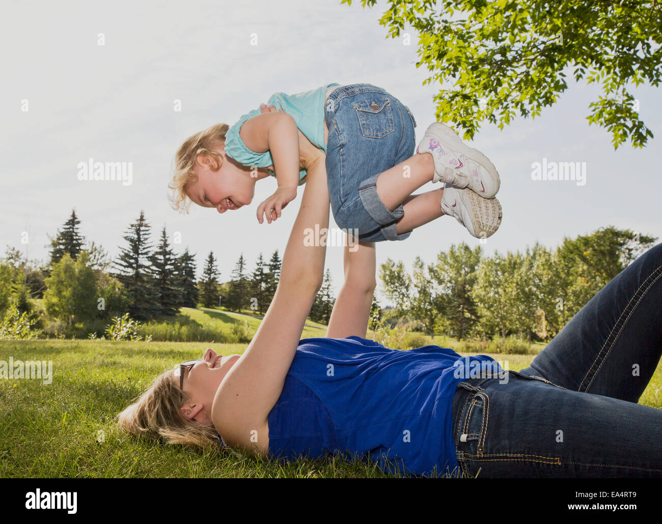 Mère tenant sa fille dans l'air dans un parc ; Edmonton, Alberta, Canada Banque D'Images