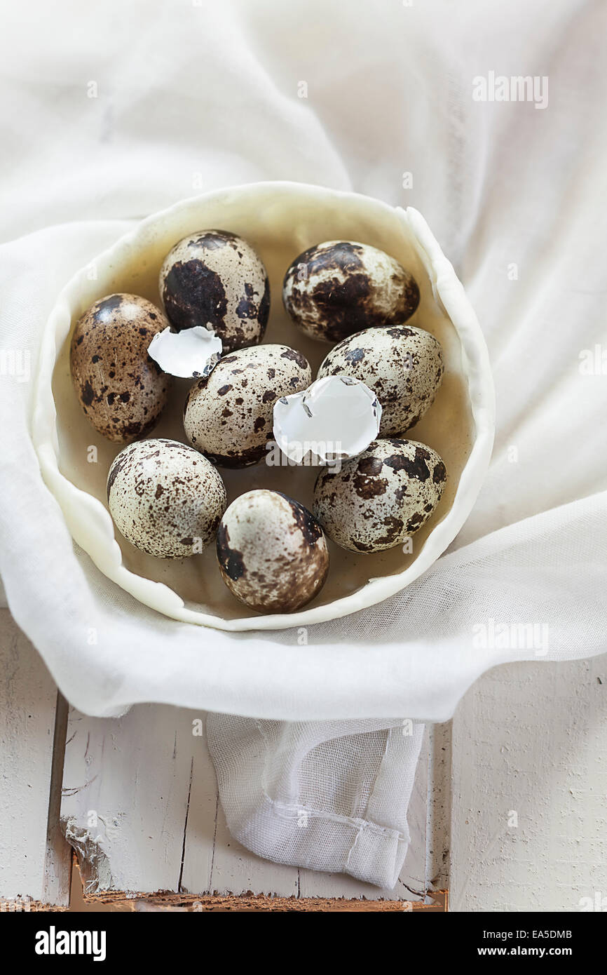 Bol d'oeufs de caille, coquilles d'œuf sur le chiffon et le bois blanc Banque D'Images