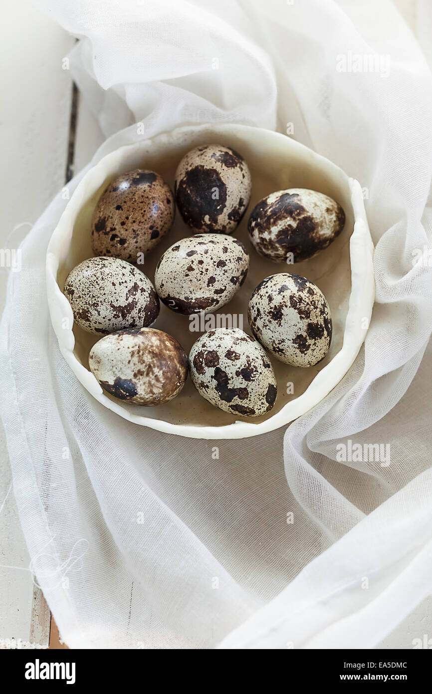 Bol d'oeufs de cailles sur un tissu blanc et bois Banque D'Images