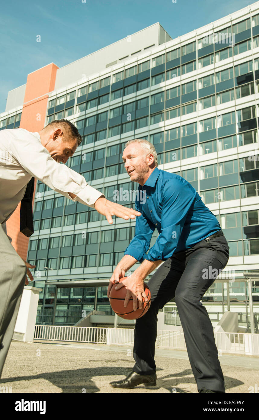 Deux hommes d'jouer au basket-ball à l'extérieur de bâtiment de bureaux Banque D'Images
