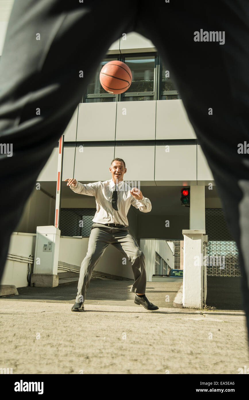 Deux hommes d'jouer au basket-ball à l'extérieur de bâtiment de bureaux Banque D'Images