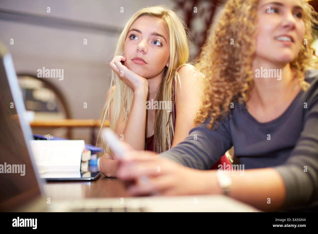 Deux élèves de sexe féminin à l'aide d'ordinateur portable dans une bibliothèque Banque D'Images