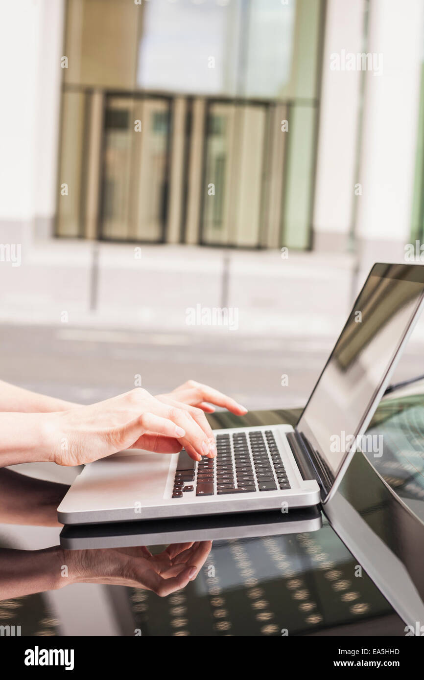 Allemagne, Hesse, Francfort, woman's hands typing on laptop debout sur coffre de voiture Banque D'Images