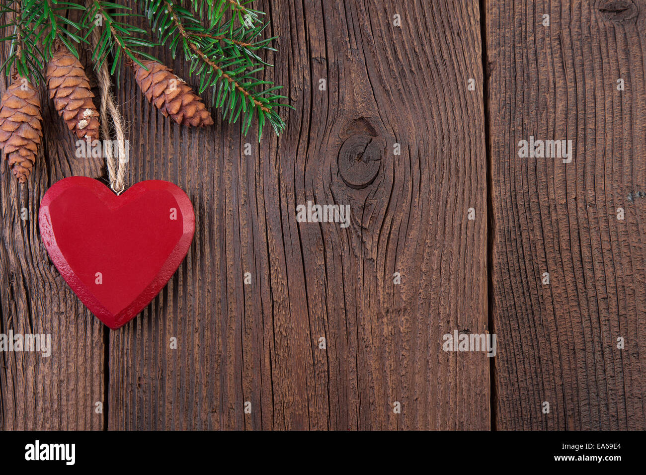 Coeur rouge avec des branches de sapin sur fond de bois Banque D'Images