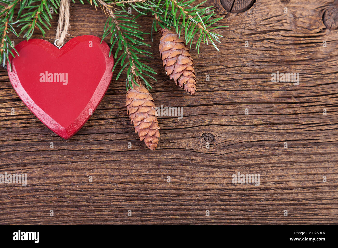 Coeur rouge avec des branches de sapin sur un fond de bois Banque D'Images