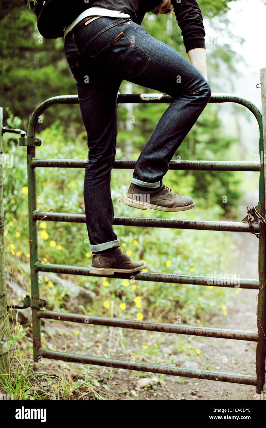 Jeune homme grimpant barrier Banque D'Images