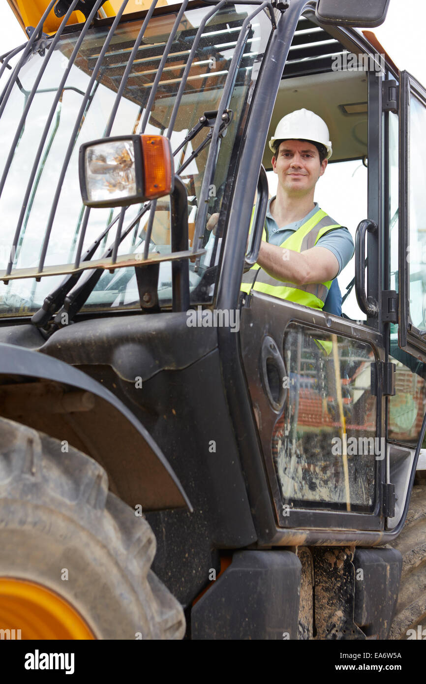 Construction Worker Driving Digger sur chantier Banque D'Images