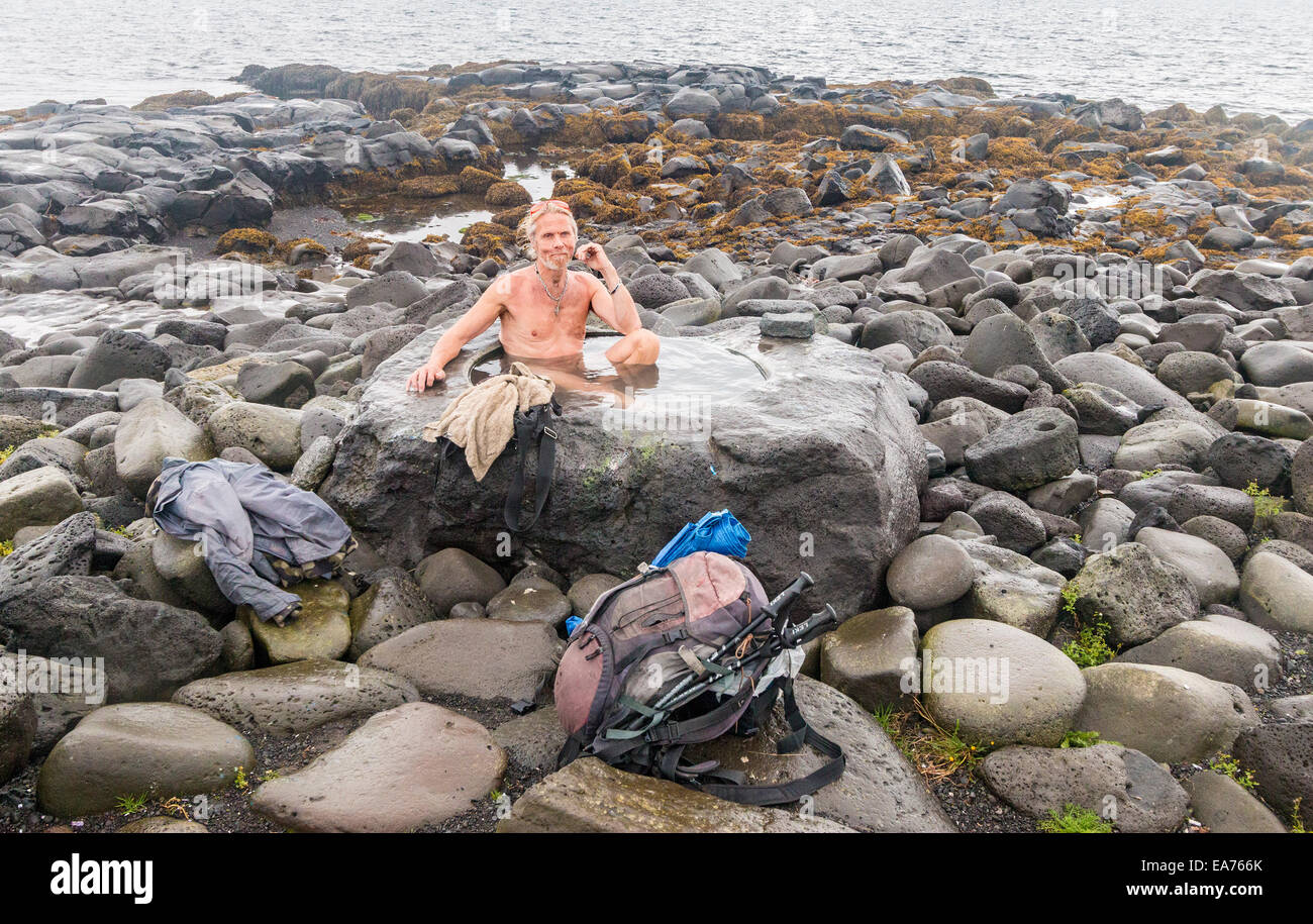 Homme de la région baigne dans un ensemble de sources chaudes naturelles dans les roches au rivage de Reykjavik. Banque D'Images