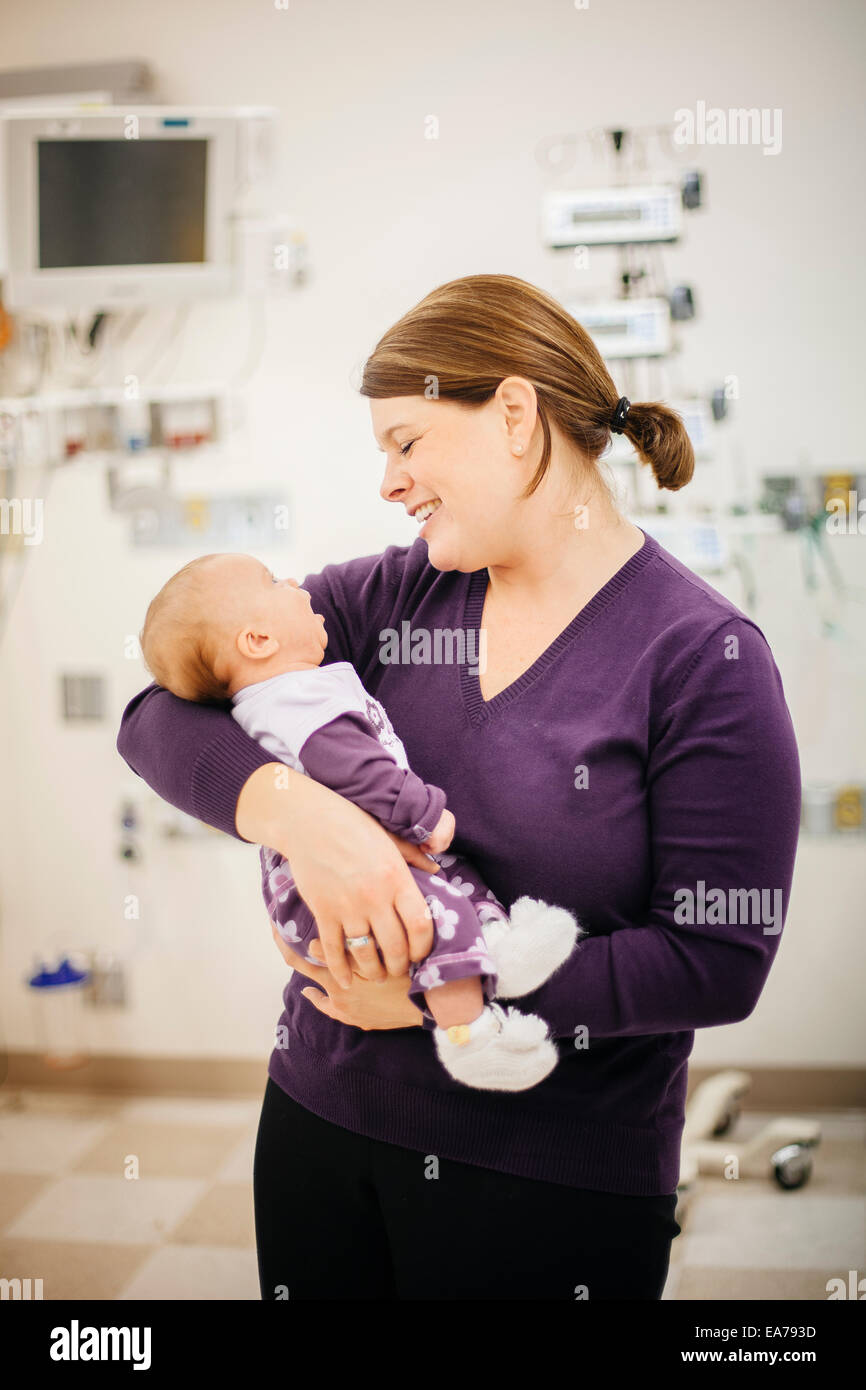Mère standing in hospital ward holding baby son (6-11 mois) Banque D'Images