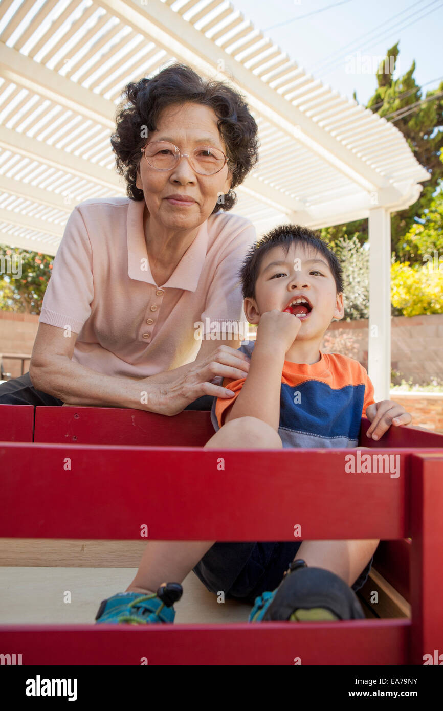 Grand-mère avec son petit-fils (2-3) posant à l'appareil photo dans le jardin Banque D'Images