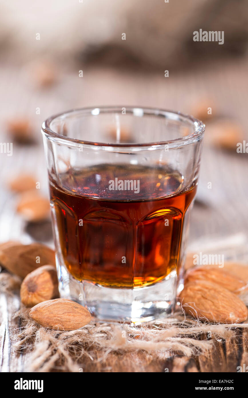 L'Amaretto tourné sur fond de bois foncé avec quelques amandes Banque D'Images