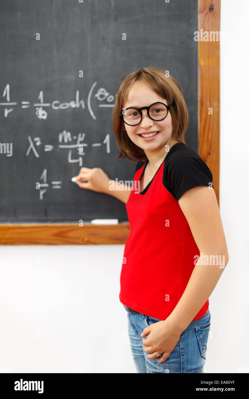 Wise school girl écrit la solution de l'équation complexe on chalkboard Banque D'Images