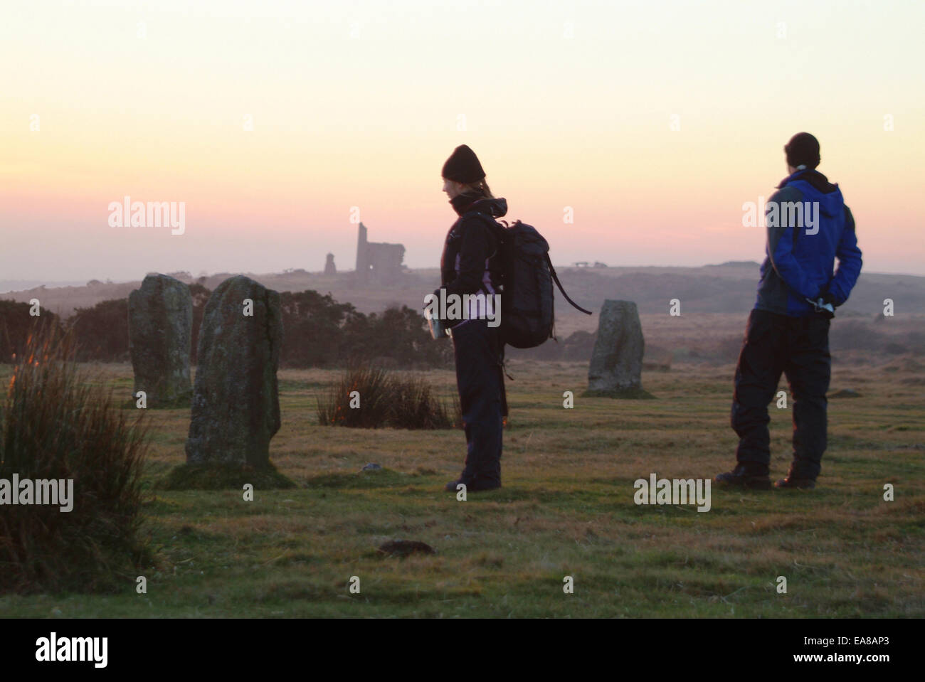 Deux randonneurs profitant de coucher du soleil à The Hurlers Stone Circle sur Bodmin Moor à larbins Caradon sud-est sud-ouest de l'Angleterre Cornwall Banque D'Images