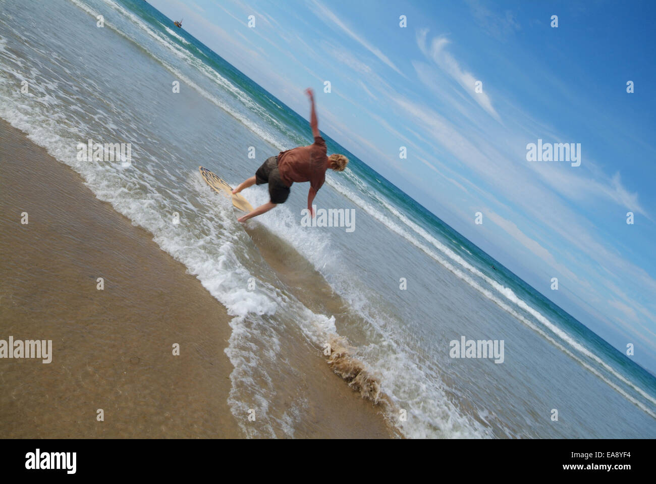 Jeune homme à bord d'écrémage le long bord de l'eau à marée basse sur la plage de Newquay sur la côte nord des Cornouailles Restormel Milieu Cornw Banque D'Images