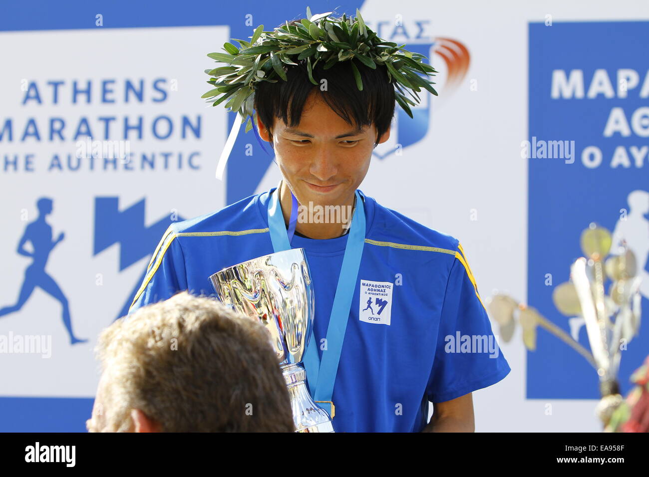 Athènes, Grèce. 9 novembre 2014. Le fastet coureur japonais du 32e Marathon d'Athènes, l'Authentique, Matsumoto Sho est représenté portant sa couronne de laurier du vainqueur et tenant son trophée. Tous les 3 médailles de la men's and women's race du 32e Marathon d'Athènes a été remporté par les Kenyans. Le men's winner Felix Kandie a établi un nouveau record de 2:10:36 pour le Marathon d'Athènes, en battant l'ancien record de 2004 par Stefano Baldini. Banque D'Images