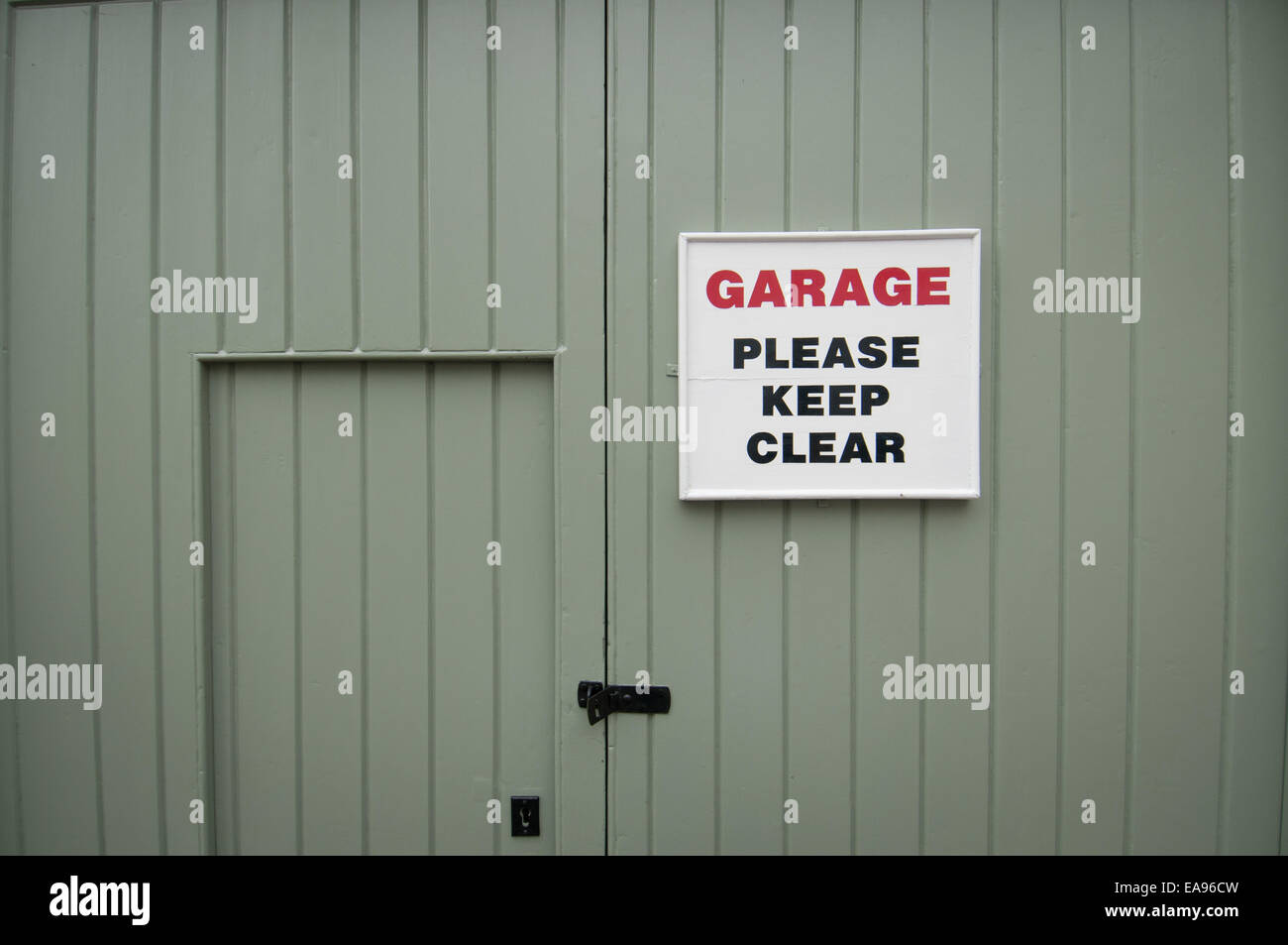 Porte de garage peint en vert avec un panneau disant 'clear' garage veuillez garder Banque D'Images
