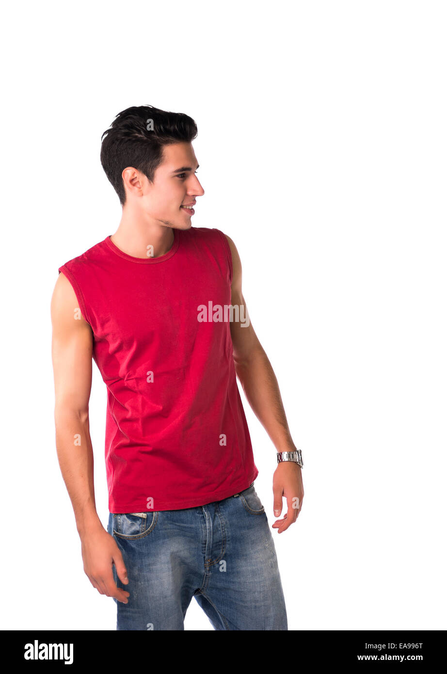 Attractive smiling young man in red T-shirt et jeans, à la recherche d'un côté à l'espace vide à côté de lui, isolated on white Banque D'Images