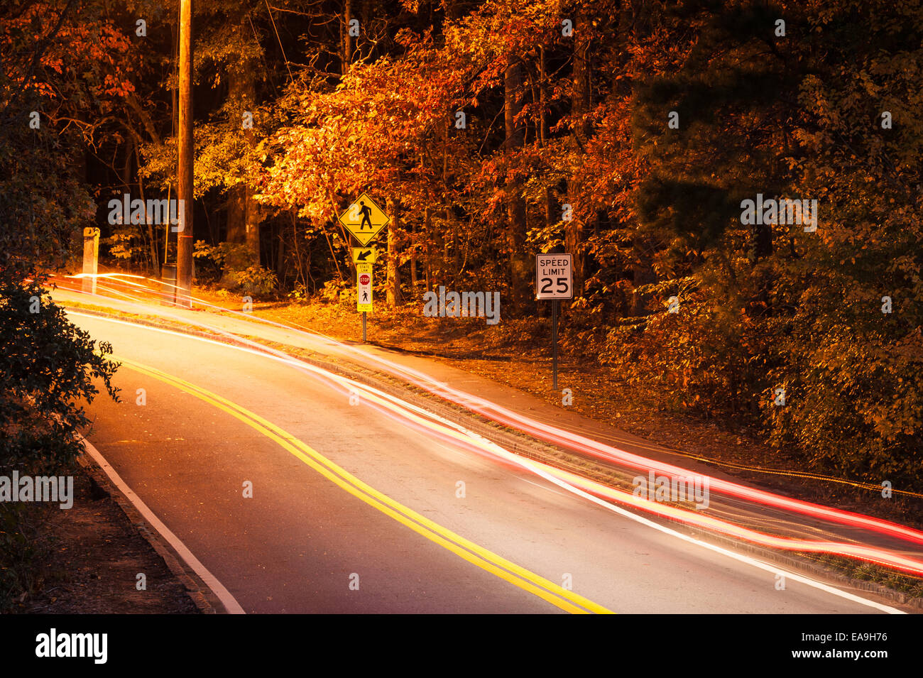 Traces légères de feux arrière apparaissent comme des sentiers d'un fantôme absent maintenant sur un véhicule routier à deux voies boisées à Stone Mountain Park. Banque D'Images