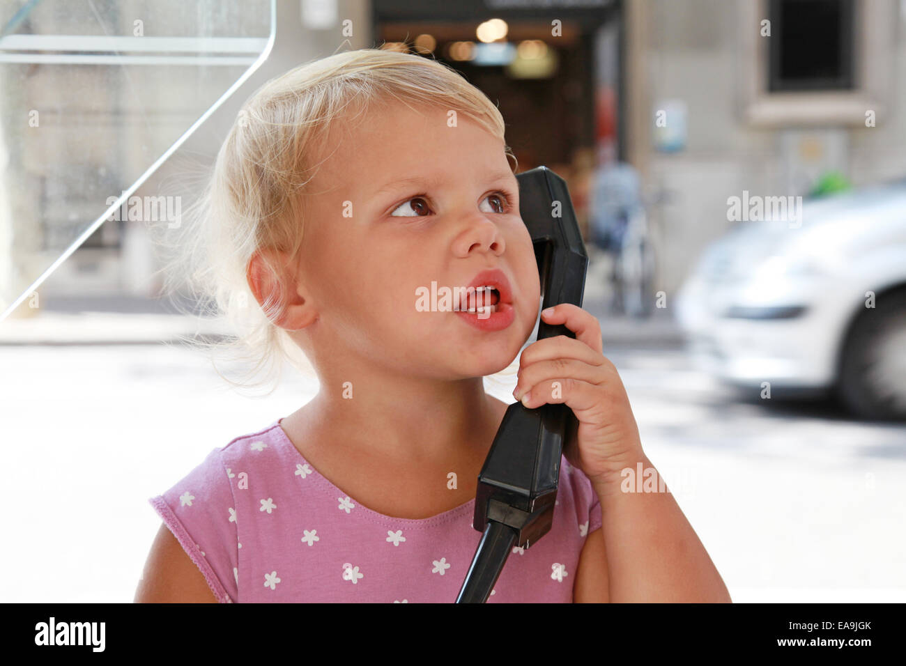 Portrait de plein air confus peu Caucasian blonde girl talking on the street phone Banque D'Images