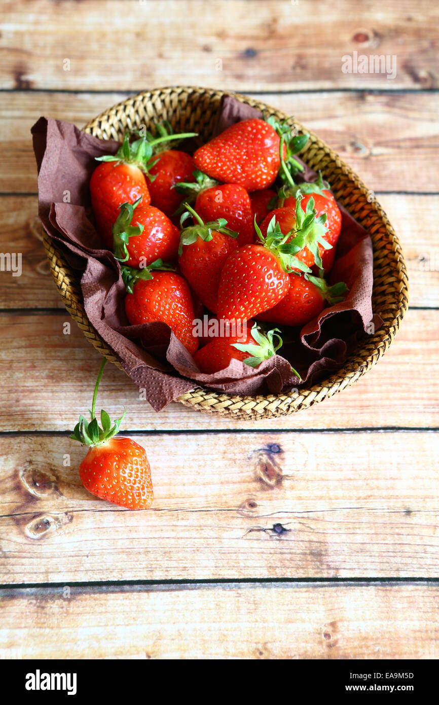 Fraises fraîches dans un panier en osier, de petits fruits mûrs, vue du dessus Banque D'Images