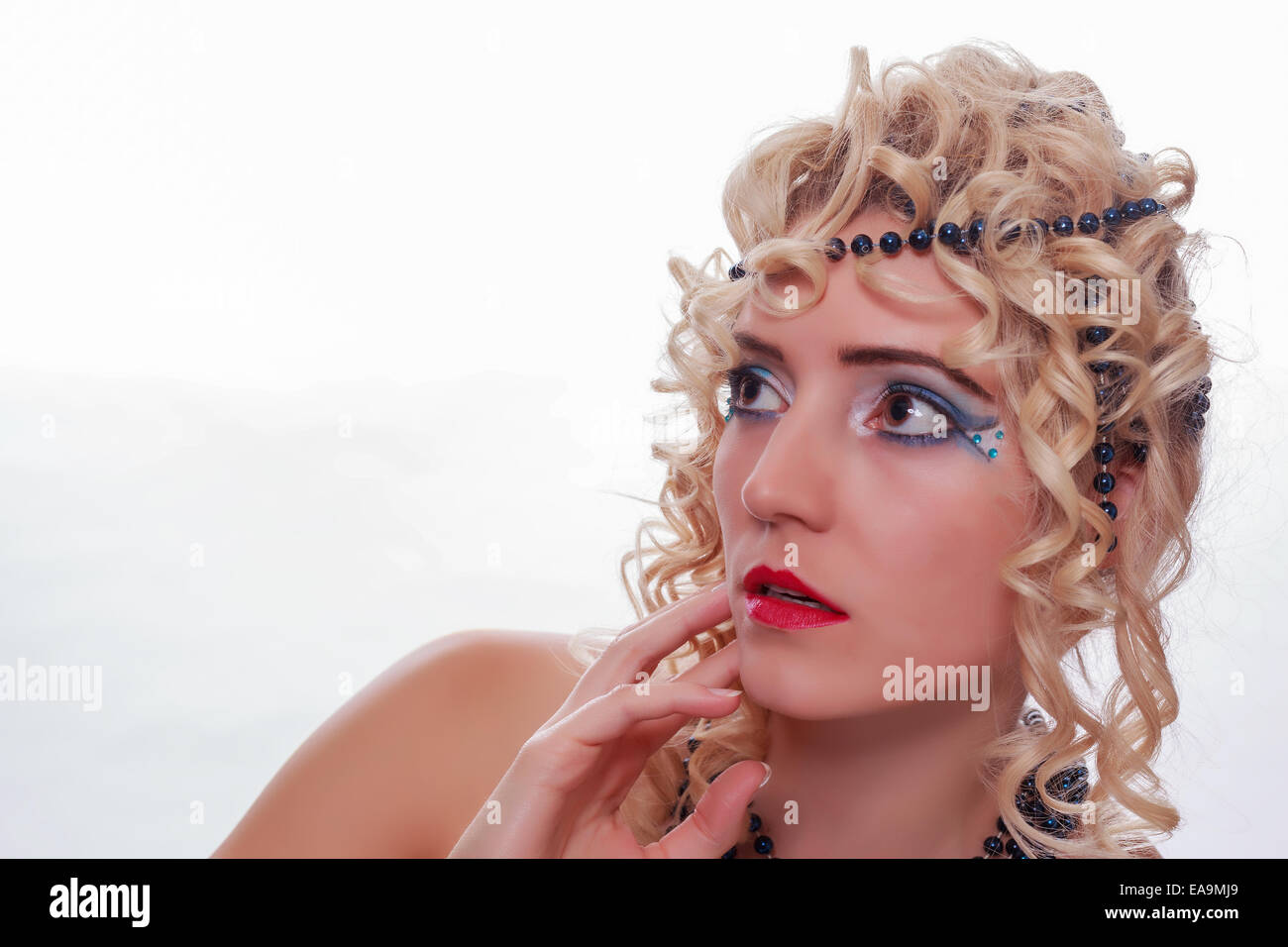 Portrait d'une femme blonde frisée avec collier de perles dans les cheveux Banque D'Images