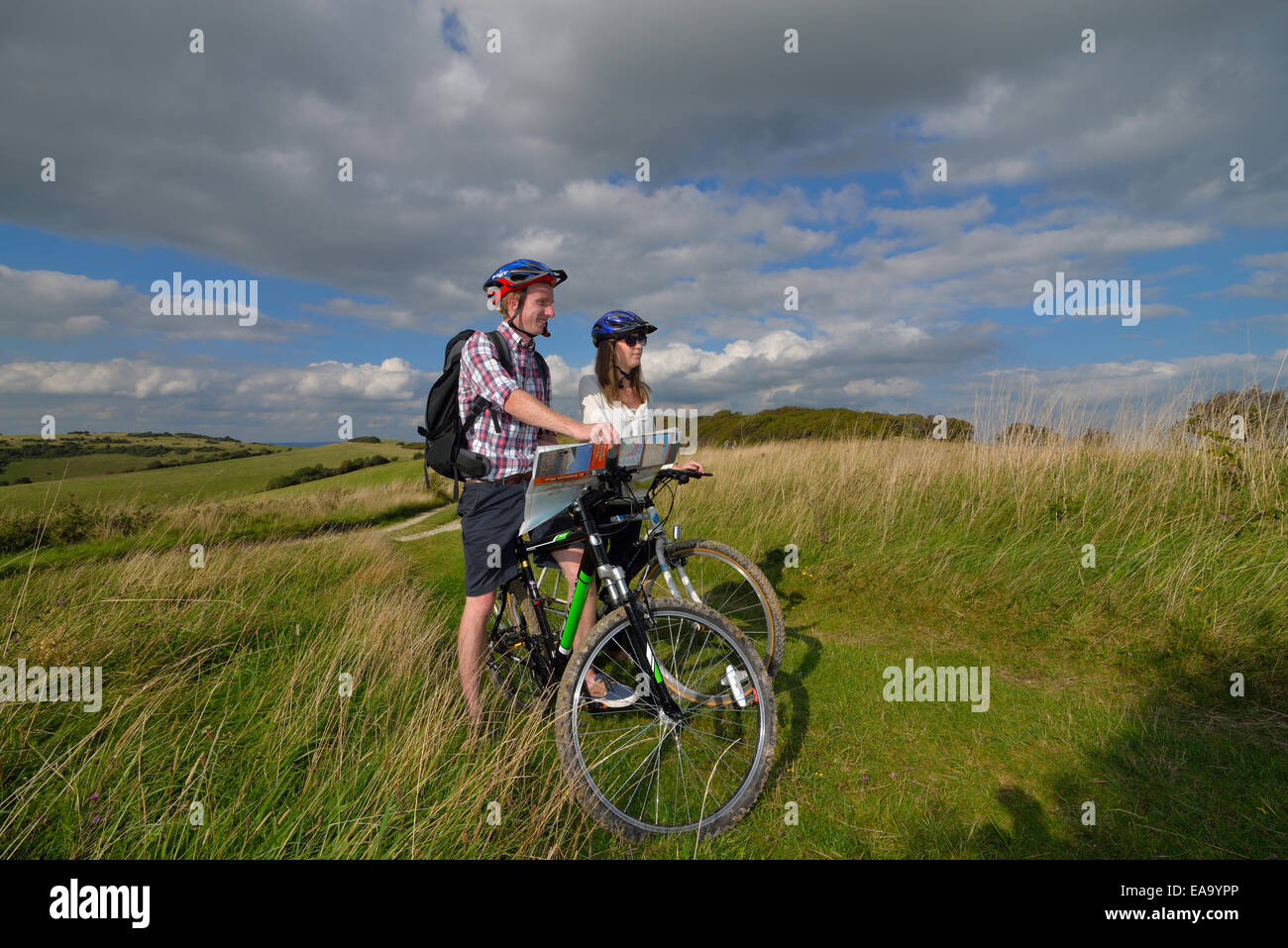 Un jeune couple de cyclistes adultes lecture de carte le long de la South Downs Way à Butts Brow, Willingdon, Eastbourne, East Sussex. UK Banque D'Images