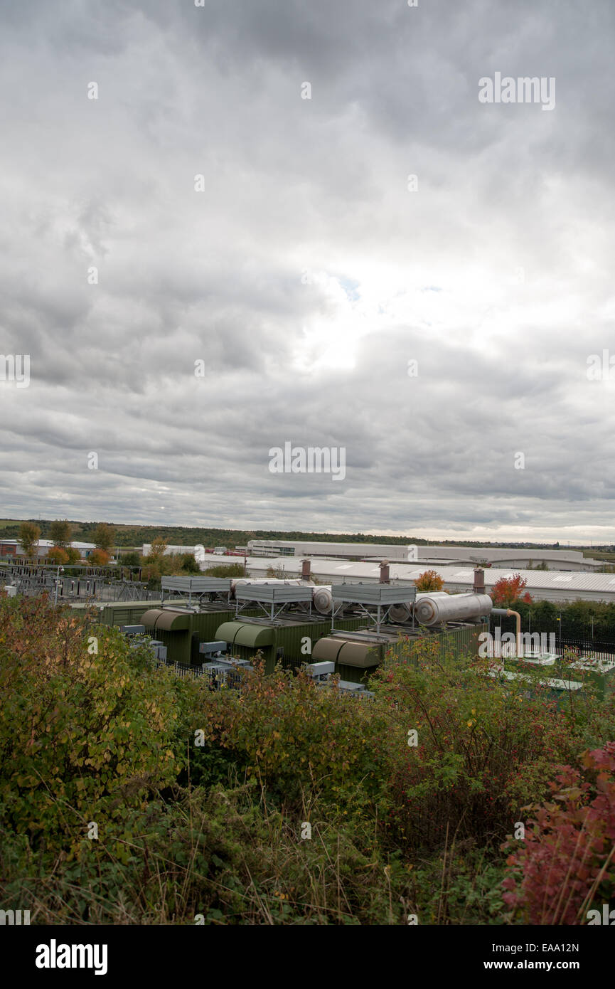 Vue large des entrepôts industriels dans un paysage rural, avec des logements lointains et un ciel nuageux sur une zone à usage mixte. Banque D'Images