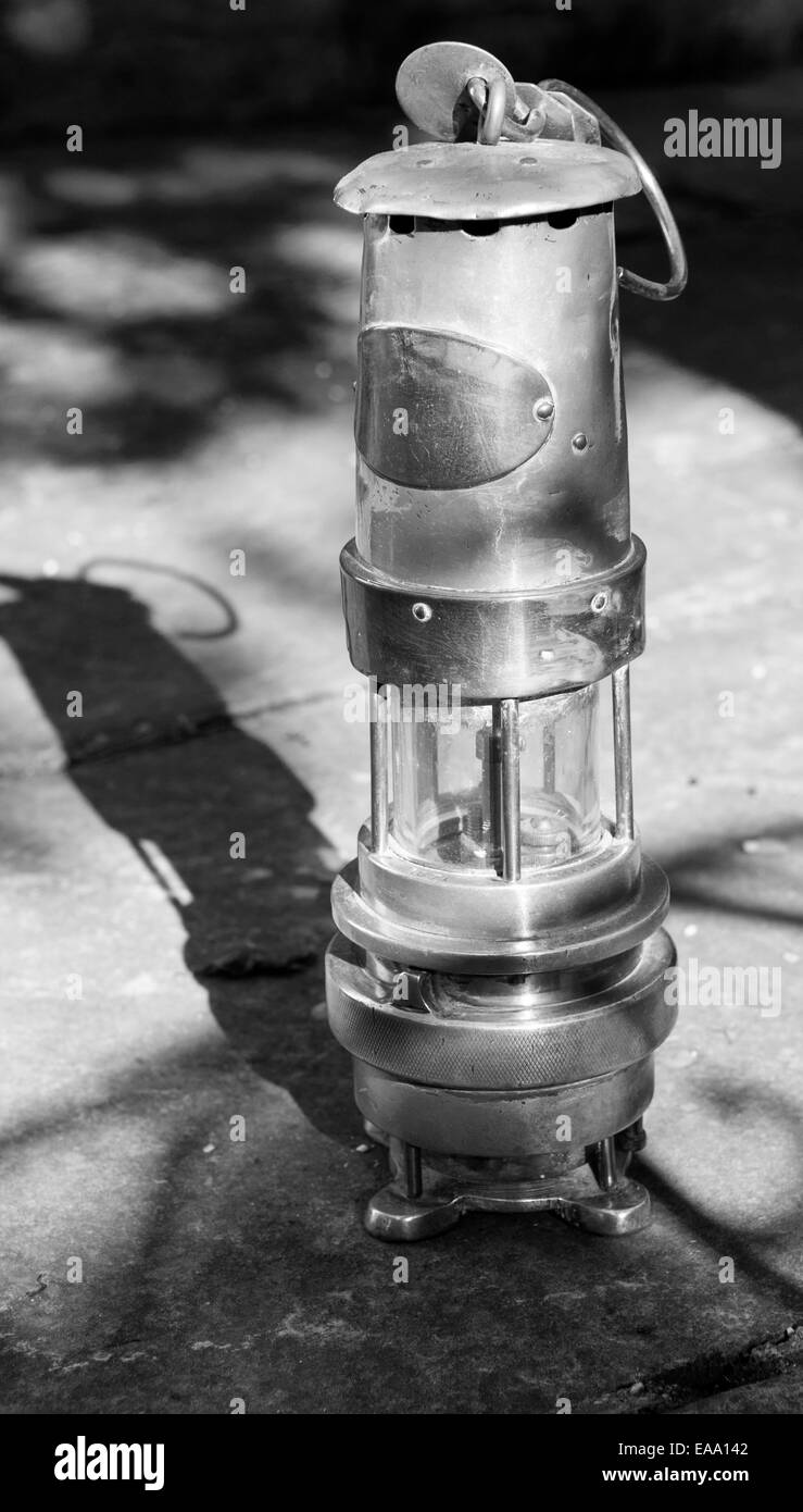 Image en noir et blanc d’une lampe de sécurité de mineurs vintage projetant une ombre sur le sol, symbolisant le patrimoine historique des mines de charbon Banque D'Images