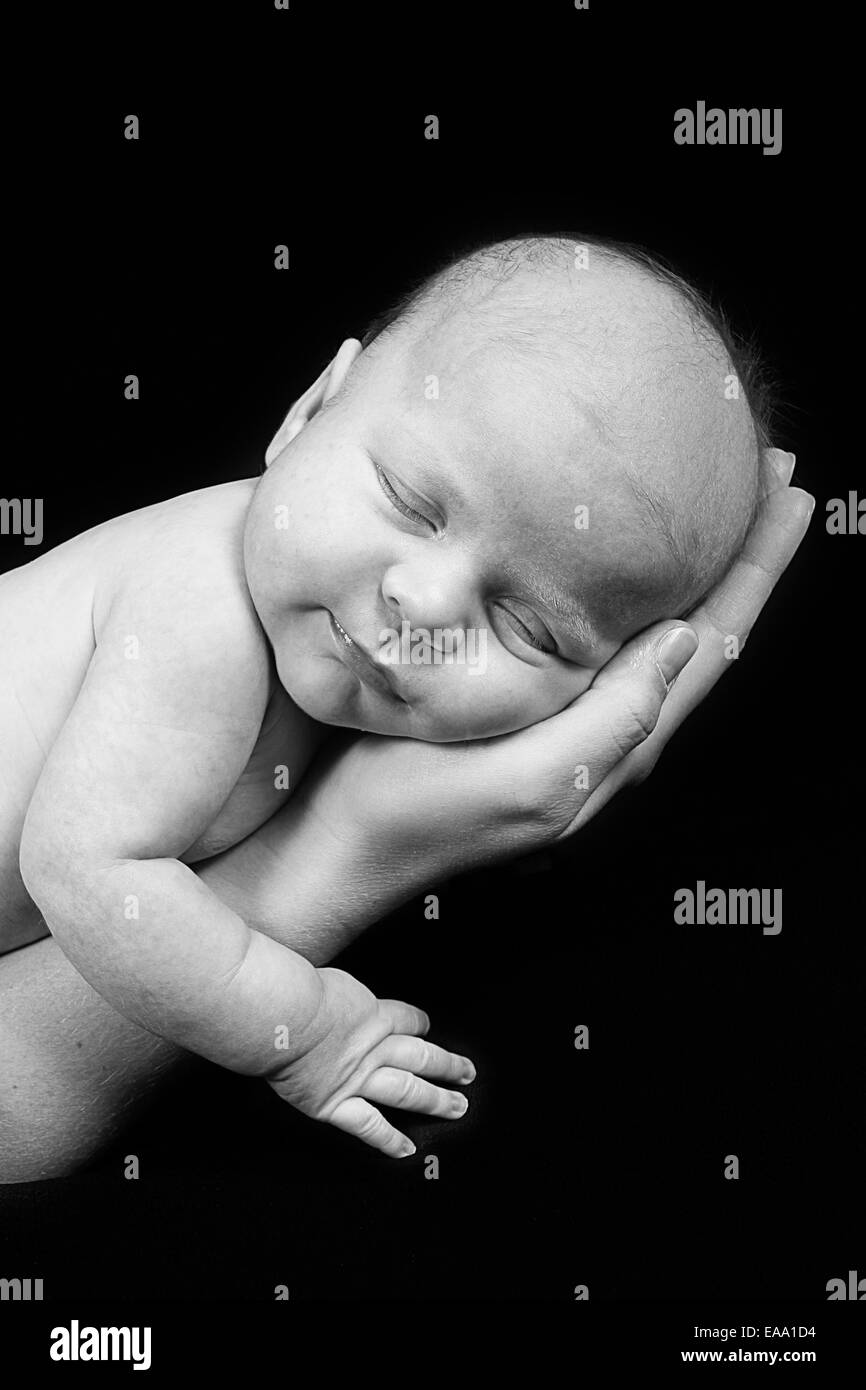 Bébé nouveau-né pris en gros plan la main de mère - noir et blanc Banque D'Images