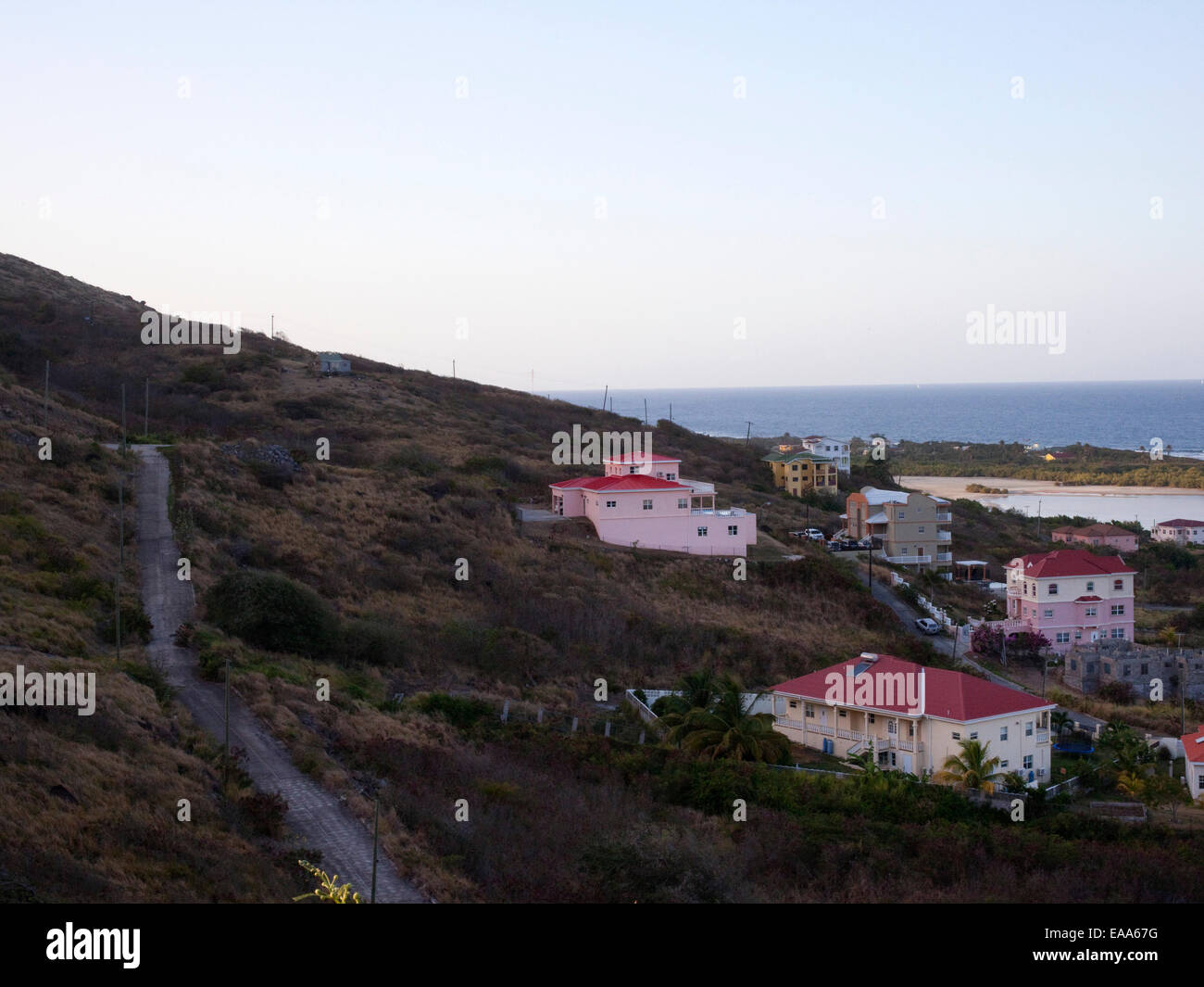Route raide et sur la colline avec des maisons donnant sur l'océan au coucher du soleil Banque D'Images