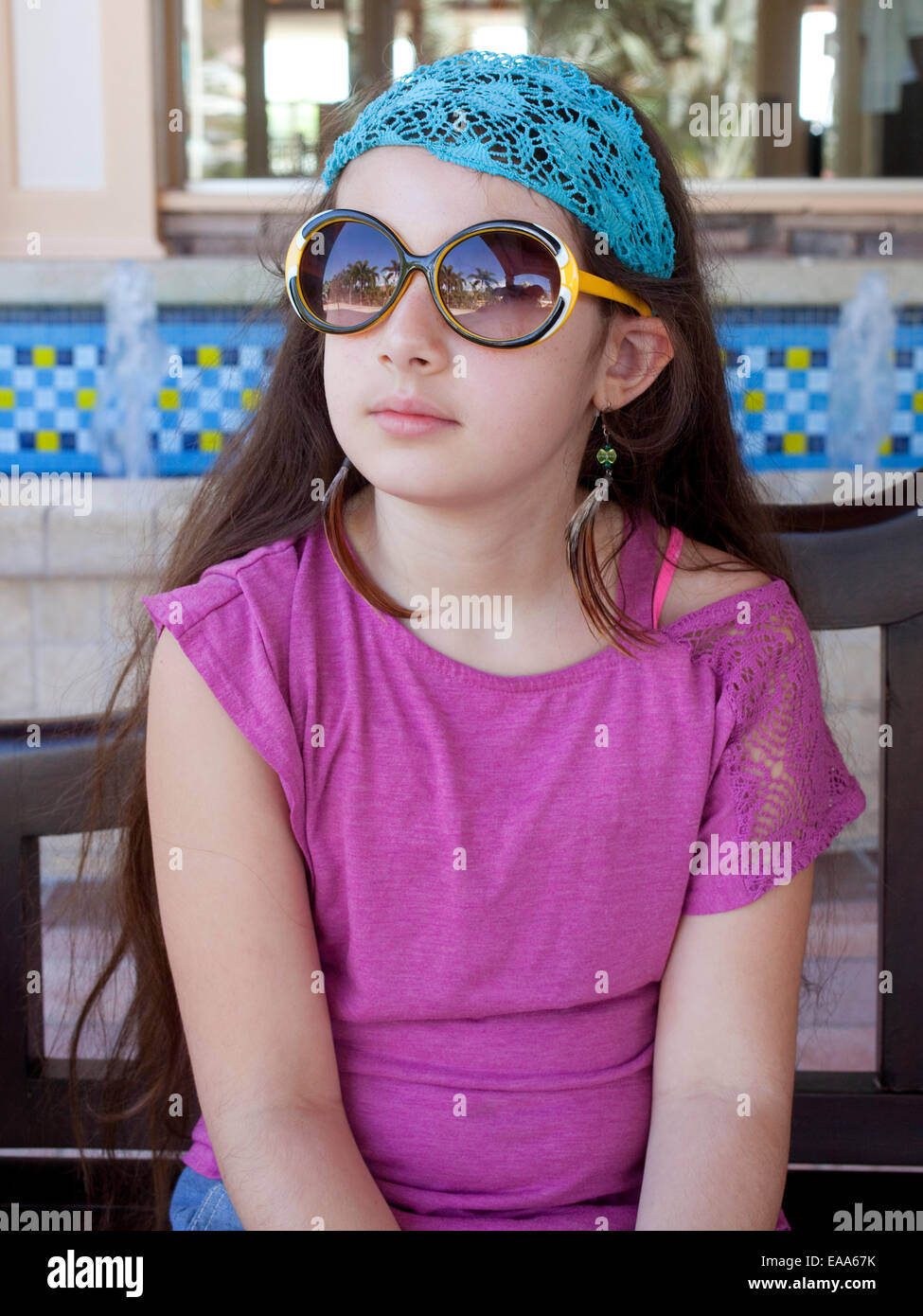 Jeune fille avec des lunettes, feather earrings et foulard Banque D'Images