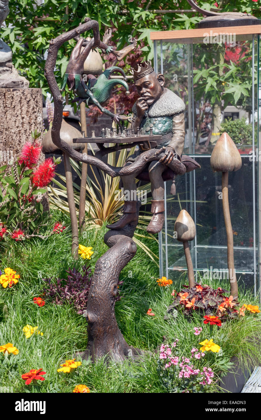Fantaisie photo d'une sculpture de métal d'un roi en jouant aux échecs dans un arbre semis dans l'herbe contenant des ornements de champignons et le plan Banque D'Images