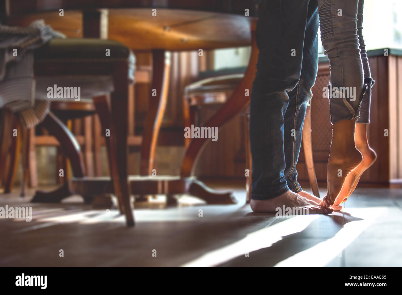 Heureux couple barefoot girl à la cuisine, debout sur la pointe des pieds  pour embrasser essayer mari Photo Stock - Alamy