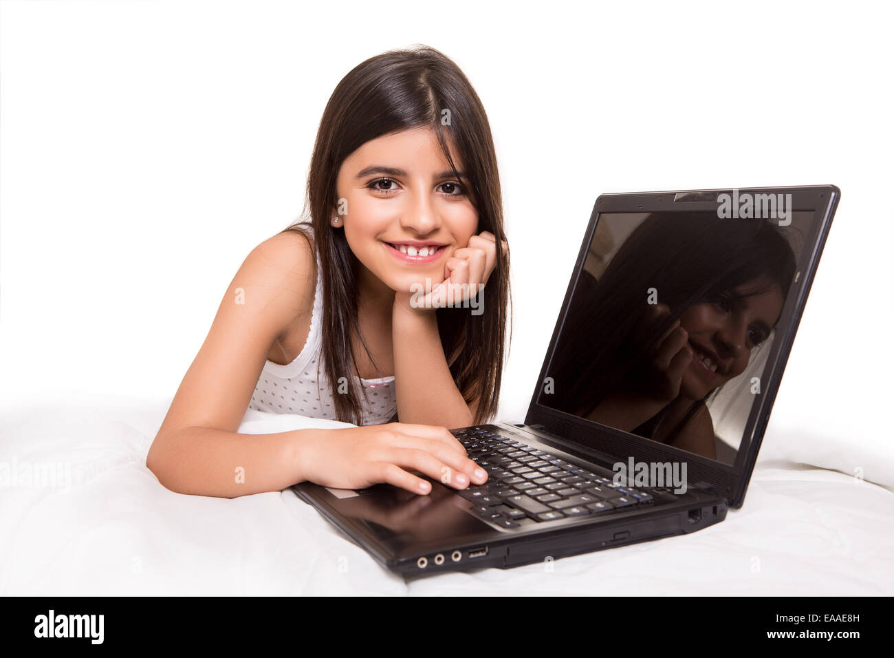 Peu de belle fille avec un ordinateur portable sur le lit Banque D'Images