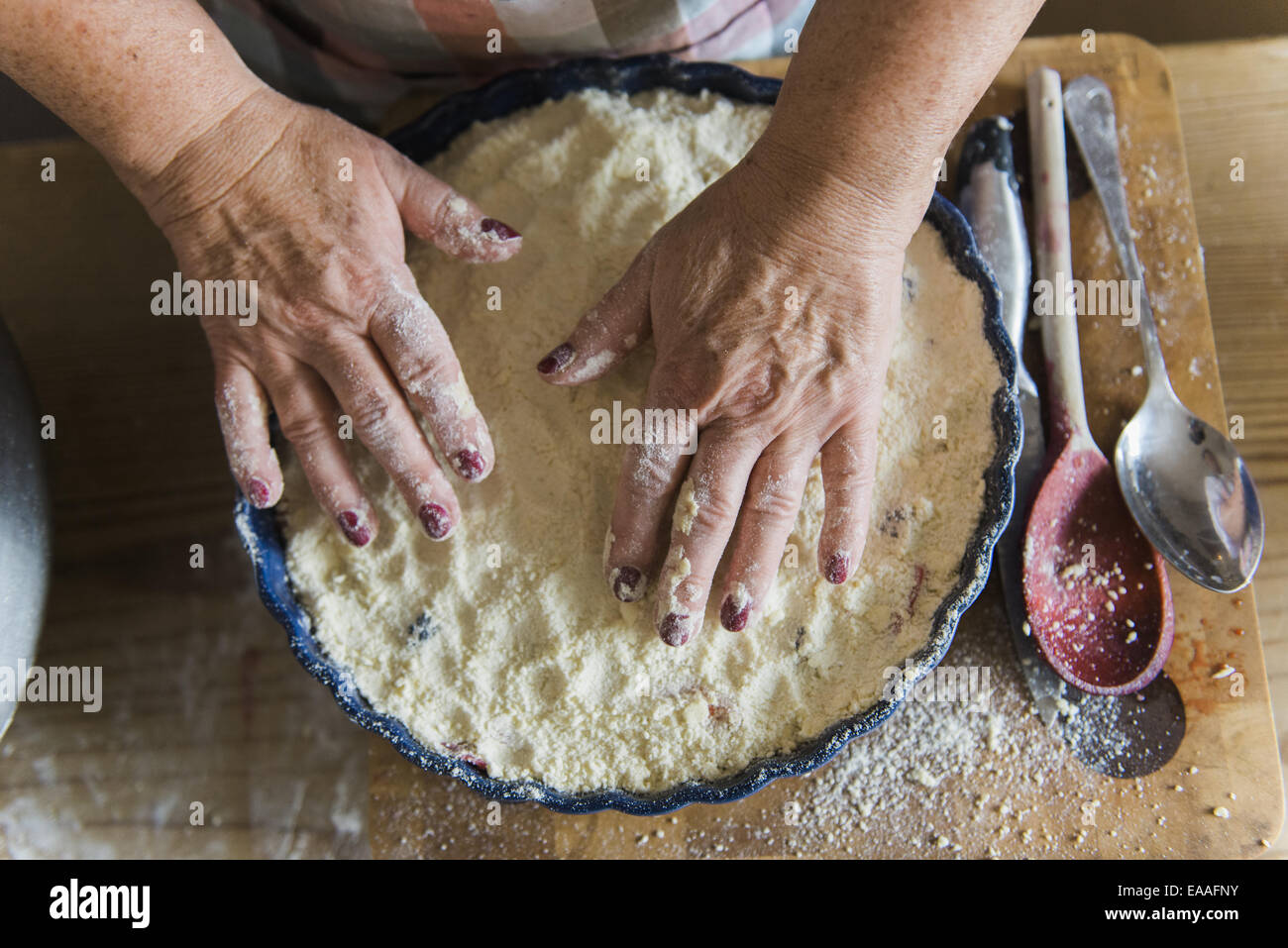 Femme tapotant émiettez le mélange dans un moule à tarte, faire un crumble aux fruits pudding. Banque D'Images