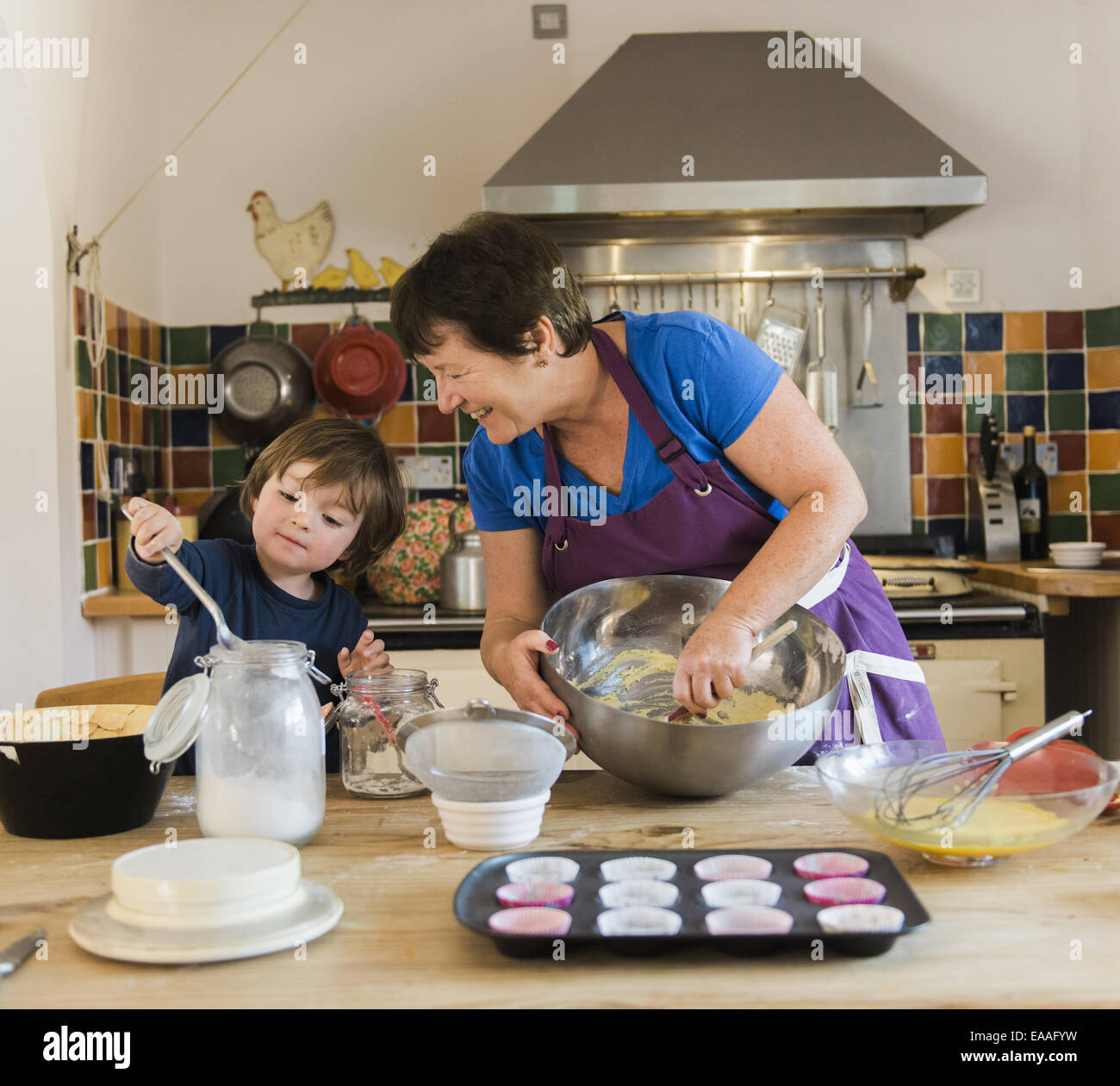 Une femme et un enfant de la cuisson à une table de cuisine, faire des gâteaux de fées. Banque D'Images