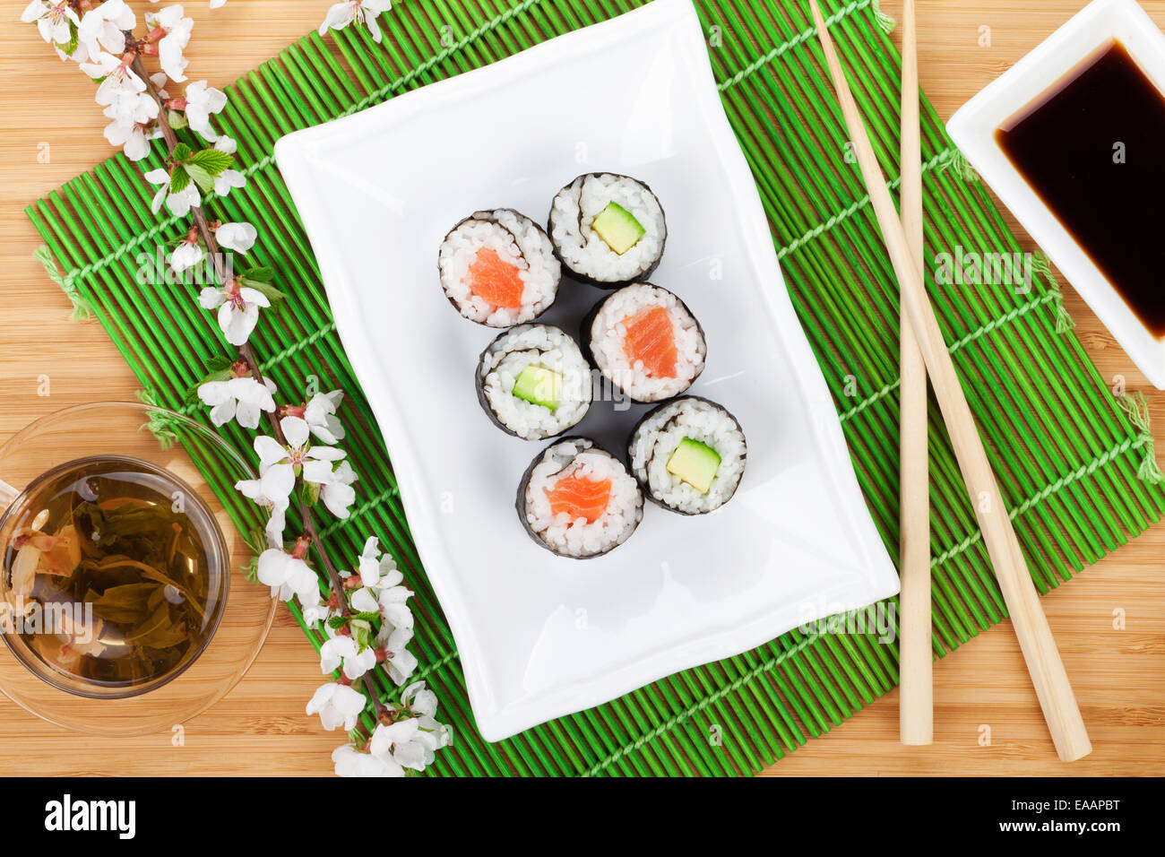 Sushi maki set, thé vert et sakura branche sur table en bambou Banque D'Images