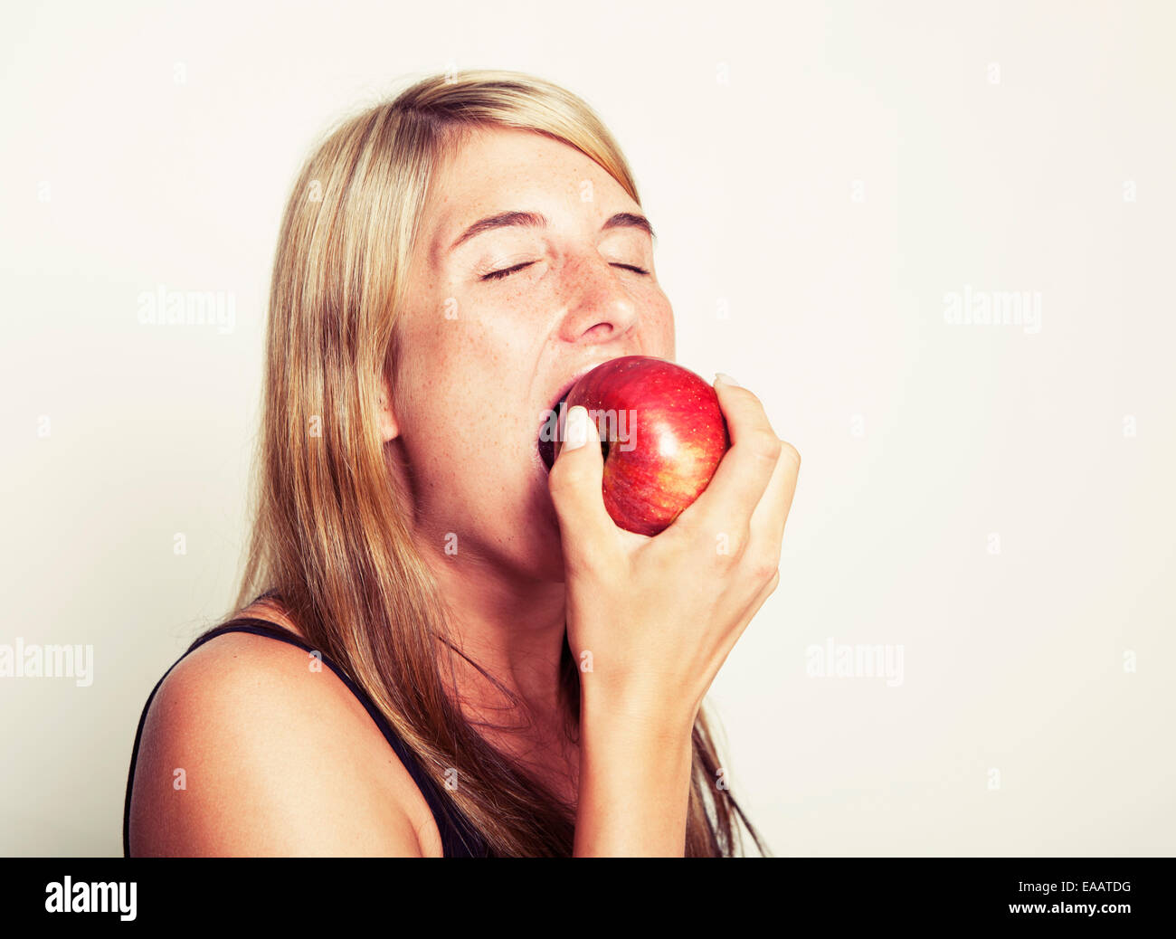 Jeune femme aux cheveux longs est titulaire d'une pomme rouge dans la main, fond blanc Banque D'Images