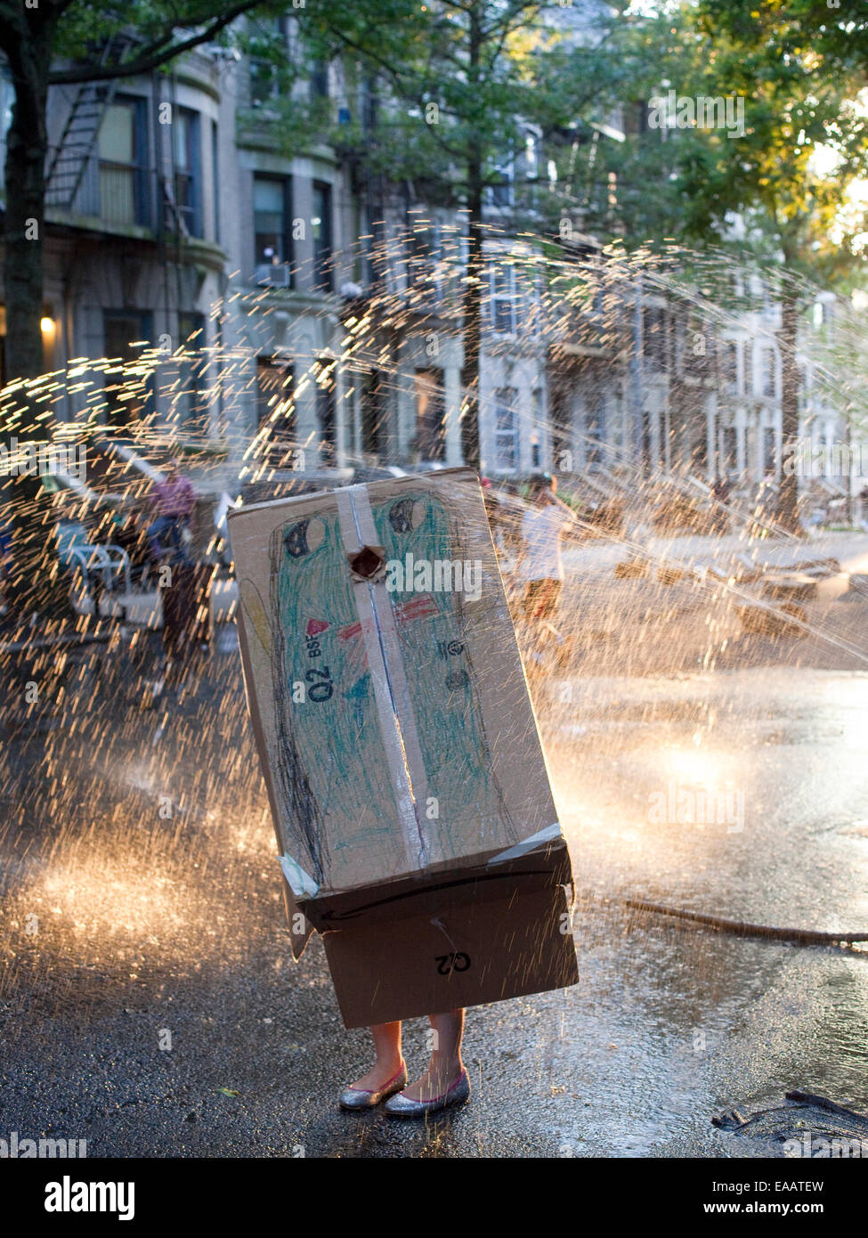 Fille en costume de pingouin jouant dans d'incendie au cours de sprinkleur Brooklyn block party. Banque D'Images