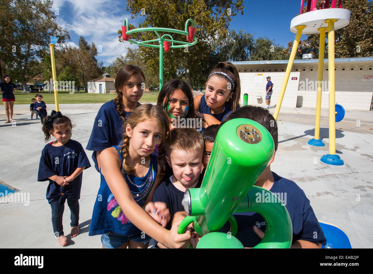 Les enfants dans un parc de pulvérisation à Bakersfield, Californie, USA. Après les quatre ans de sécheresse, Bakersfield est maintenant le plus sec des villes des USA. Toutes les villes parcs de pulvérisation ont été fermées comme il n'y a plus assez d'eau pour les faire fonctionner. Banque D'Images