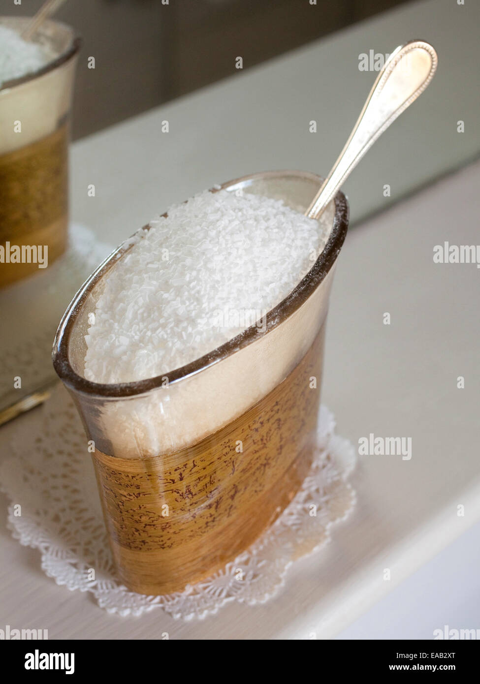 Sels de bain et cuillère en argent dans des contenants de verre dans la salle de bains. Banque D'Images