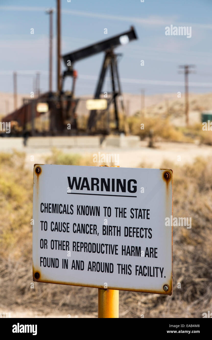 Un signe sur le cancer et d'anomalies congénitales dans le coucher du soleil à Midway Oilfield Maricopa, Bakersfield, Californie, USA. À la suite d'une sécheresse sans précédent de quatre ans, Bakersfield est maintenant la ville la plus sèche de l'USA, entraîné par le changement climatique. Les Américains ne parviennent pas toujours à faire le lien entre leur dépendance aux combustibles fossiles et les changements climatiques. Banque D'Images