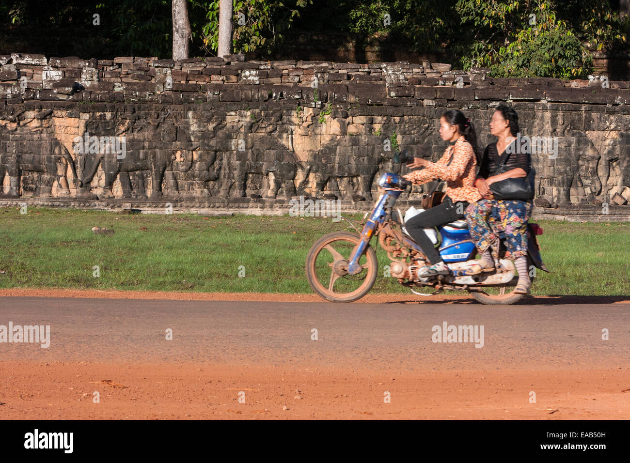 Cambodge, Angkor Thom. Les femmes sur moto passant la Terrasse des éléphants. Banque D'Images
