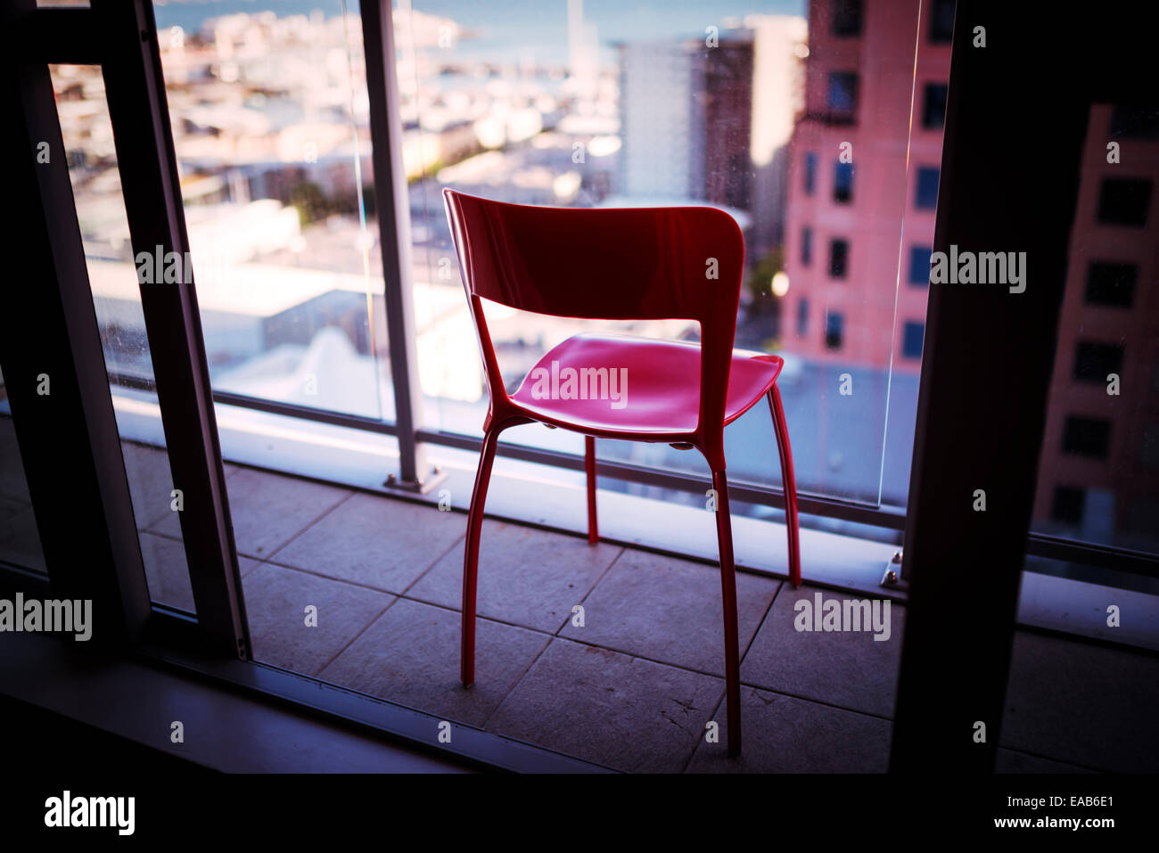 Chaise rouge sur un balcon d'immeuble Banque D'Images