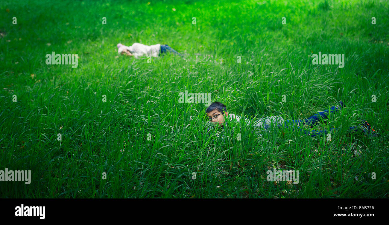 Se cacher dans l'herbe longue. Garçon et fille dans la prairie. Banque D'Images