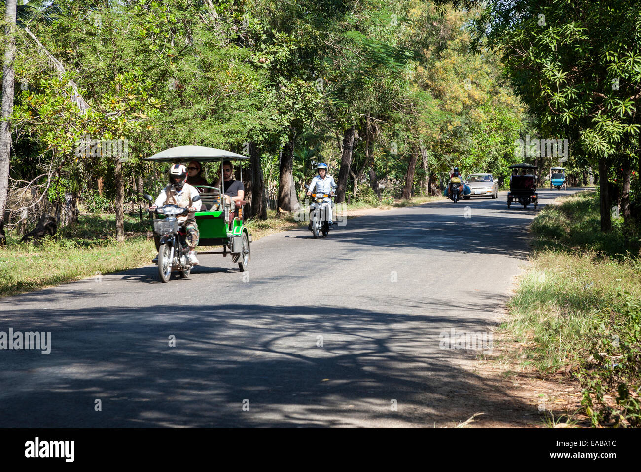 Le Cambodge. Le trafic sur une route de campagne. Les touristes dans un Motorbike-Taxi. Banque D'Images